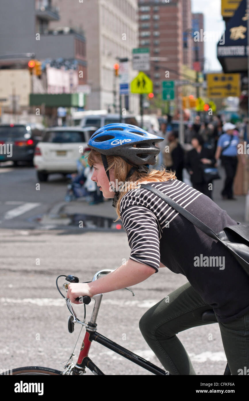 A woman in New York City rides her bike on heavily traveled city streets. Stock Photo