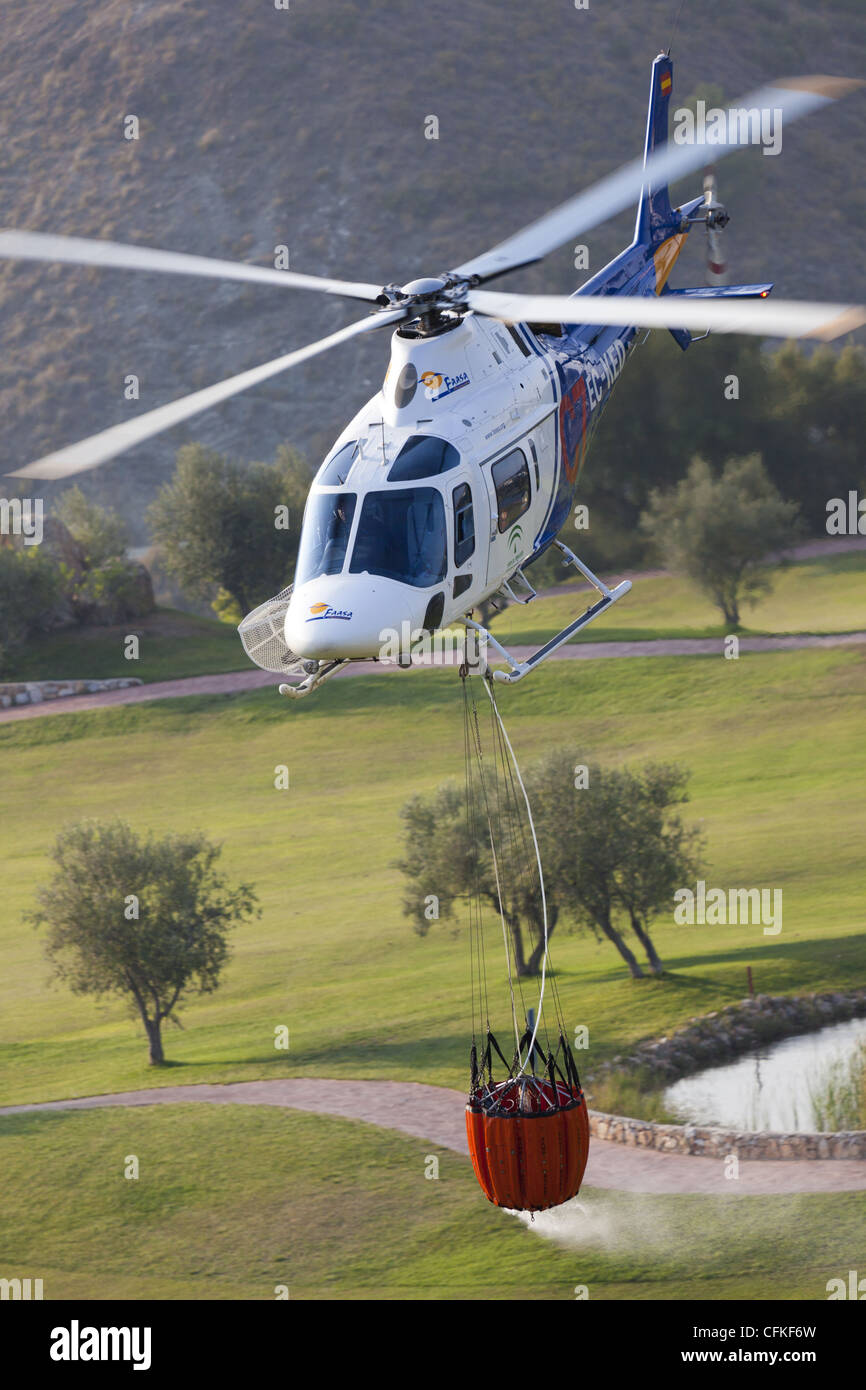 Fire-fighting  helicopter Agusta A 119 Koala of the FAASA Group picking up water from Alhaurin Golf to drop on a nearby fire Stock Photo