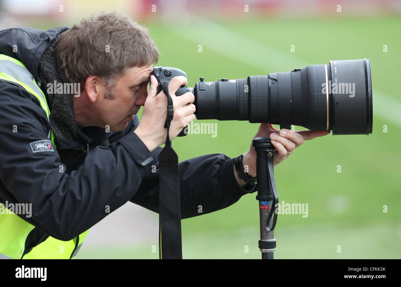 A Press photographer looks through the viewfinder whilst photographing a sports event. Picture by James Boardman. Stock Photo