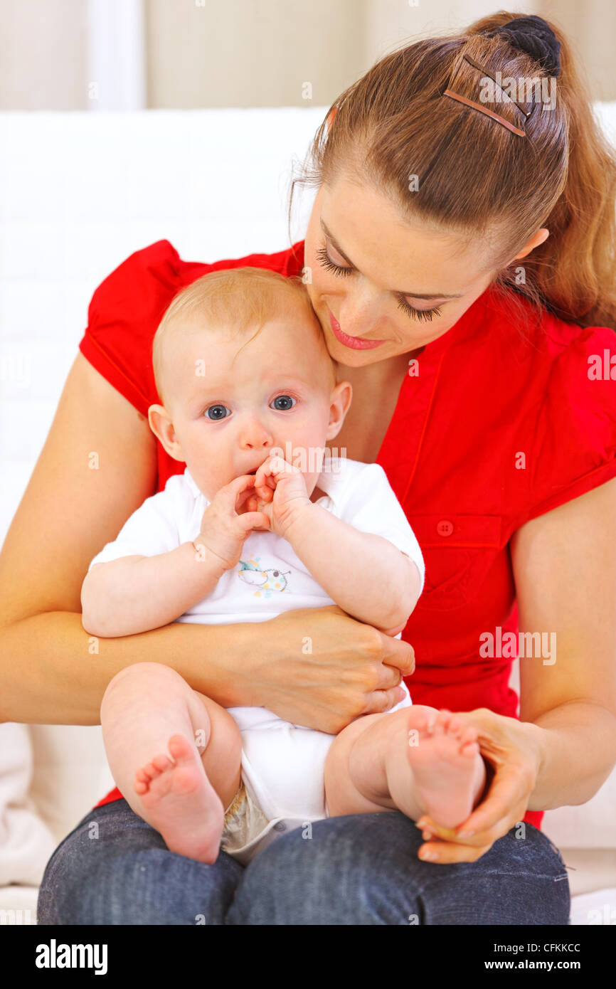 Baby putting his hands in mouth while sitting on mother laps Stock Photo Alamy