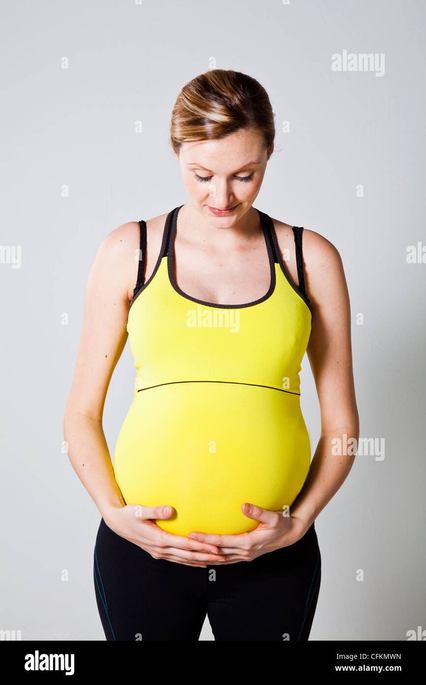 Beautiful young pregnant woman holding her tummy Stock Photo - Alamy