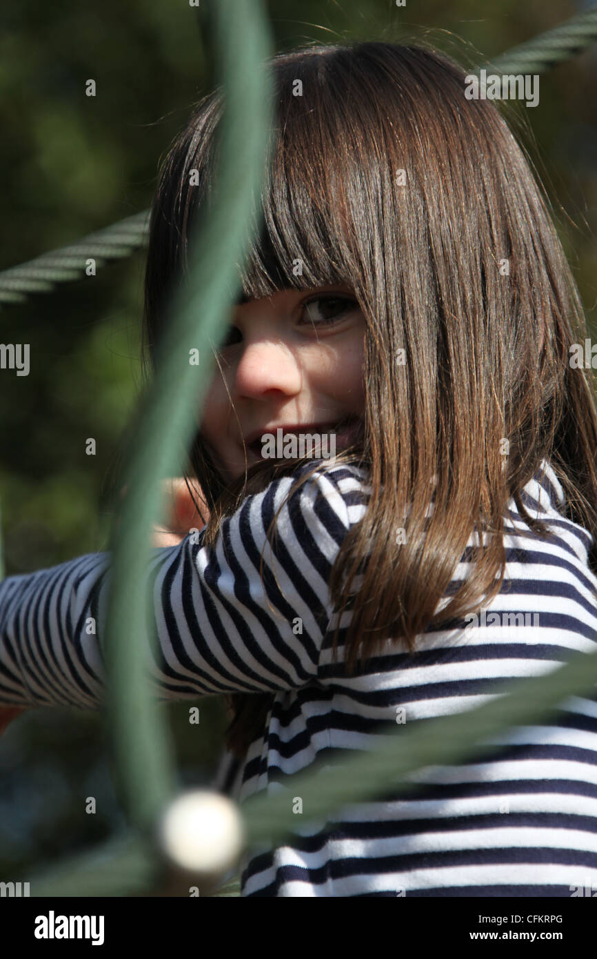 Pretty young British girl aged four years old playing in a swing park. Stock Photo