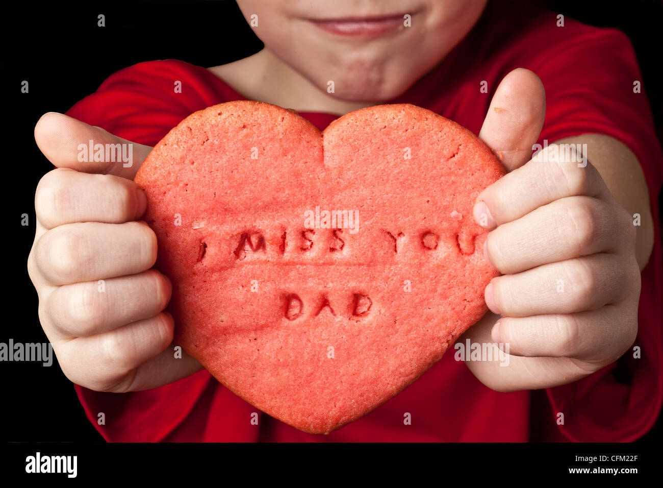 little boy holds red heart shaped cookie which reads 