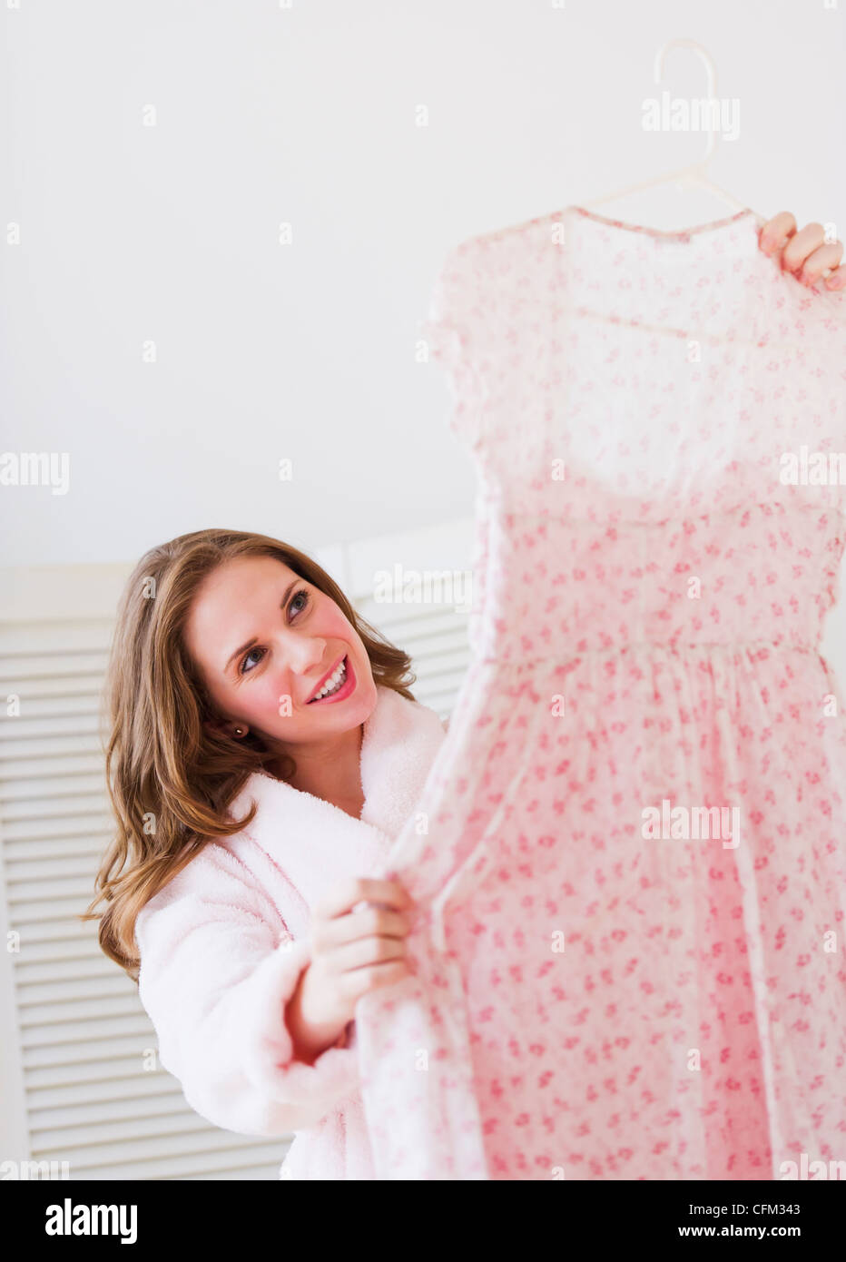 USA, New Jersey, Jersey City, Young woman holding dress in bedroom Stock Photo