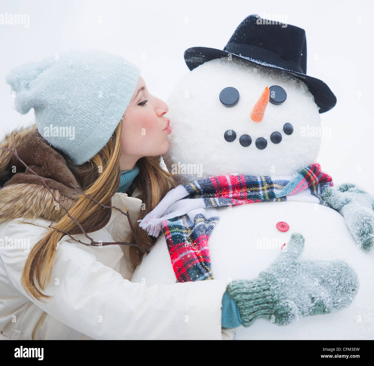 USA, New Jersey, Jersey City, young woman kissing snowman Stock Photo