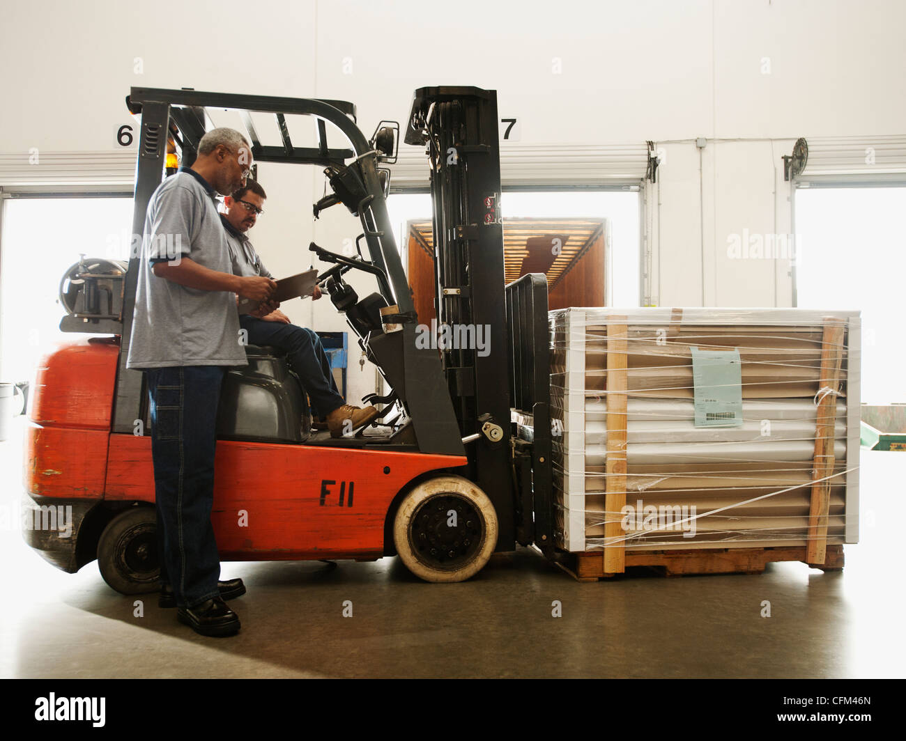 USA, California, Santa Ana, Warehouse workers talking by forklift truck