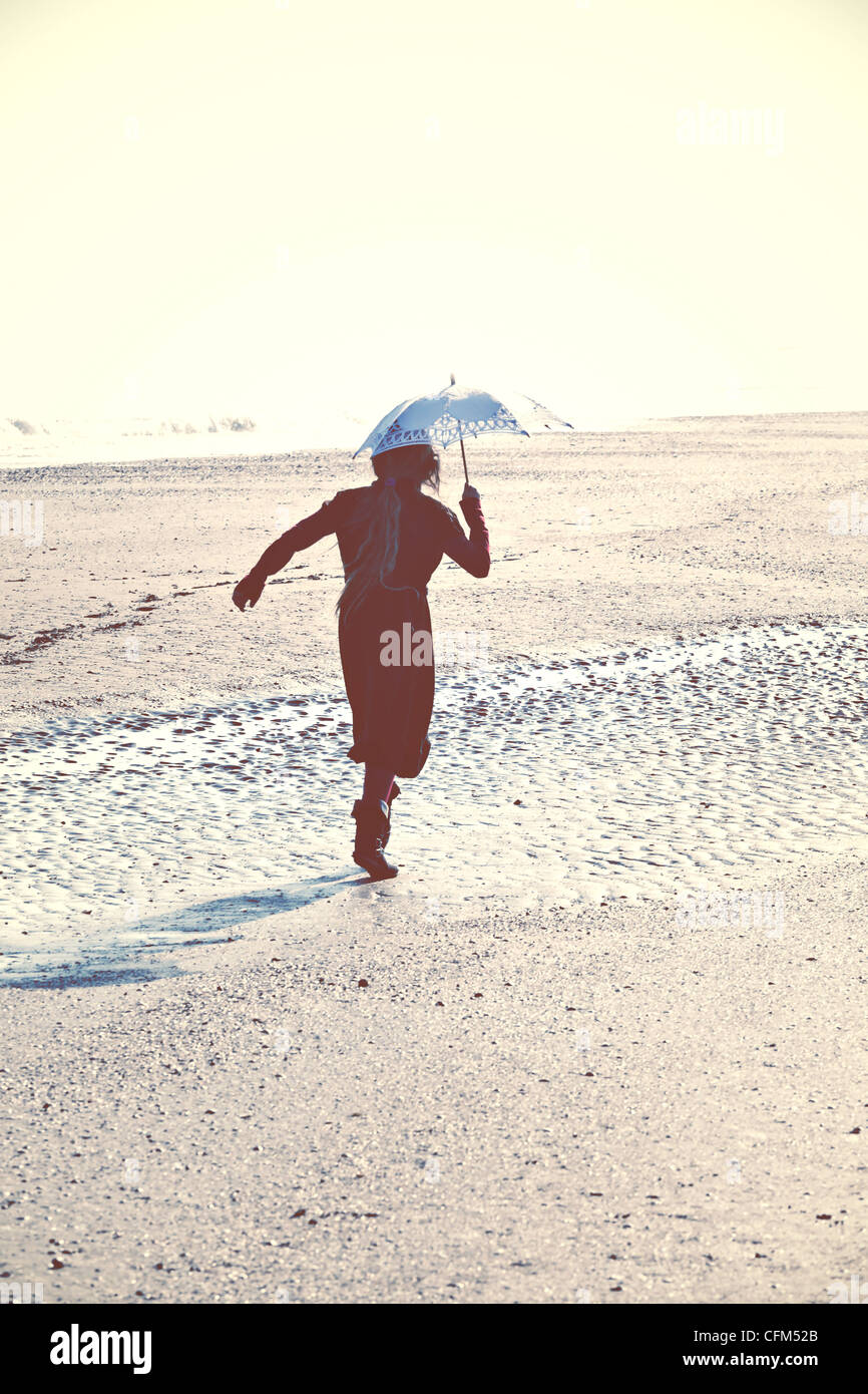 Girl running on beach with umbrella Stock Photo