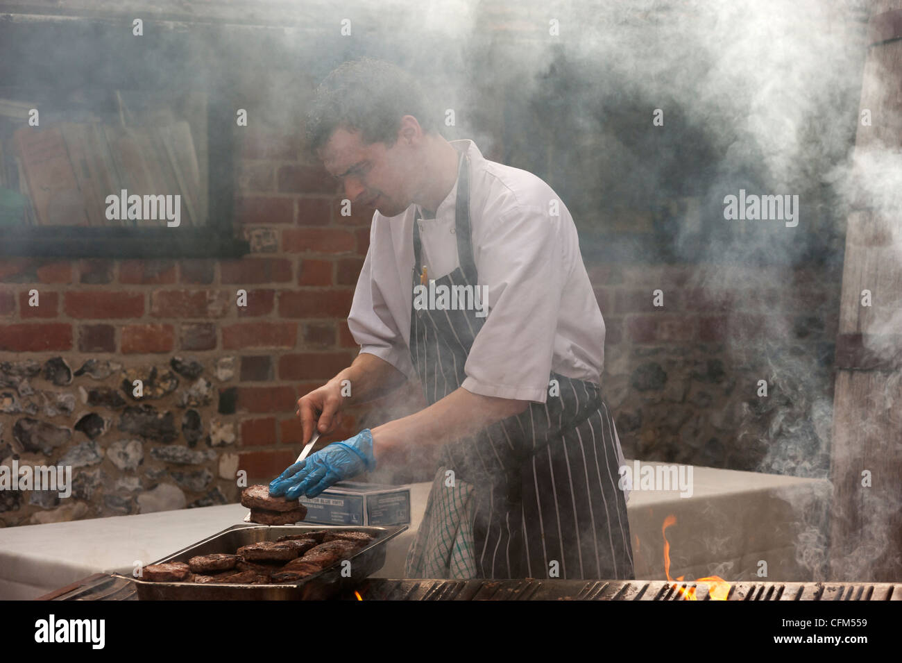 Man cooking meat on an outdoors barbecue Stock Photo - Alamy