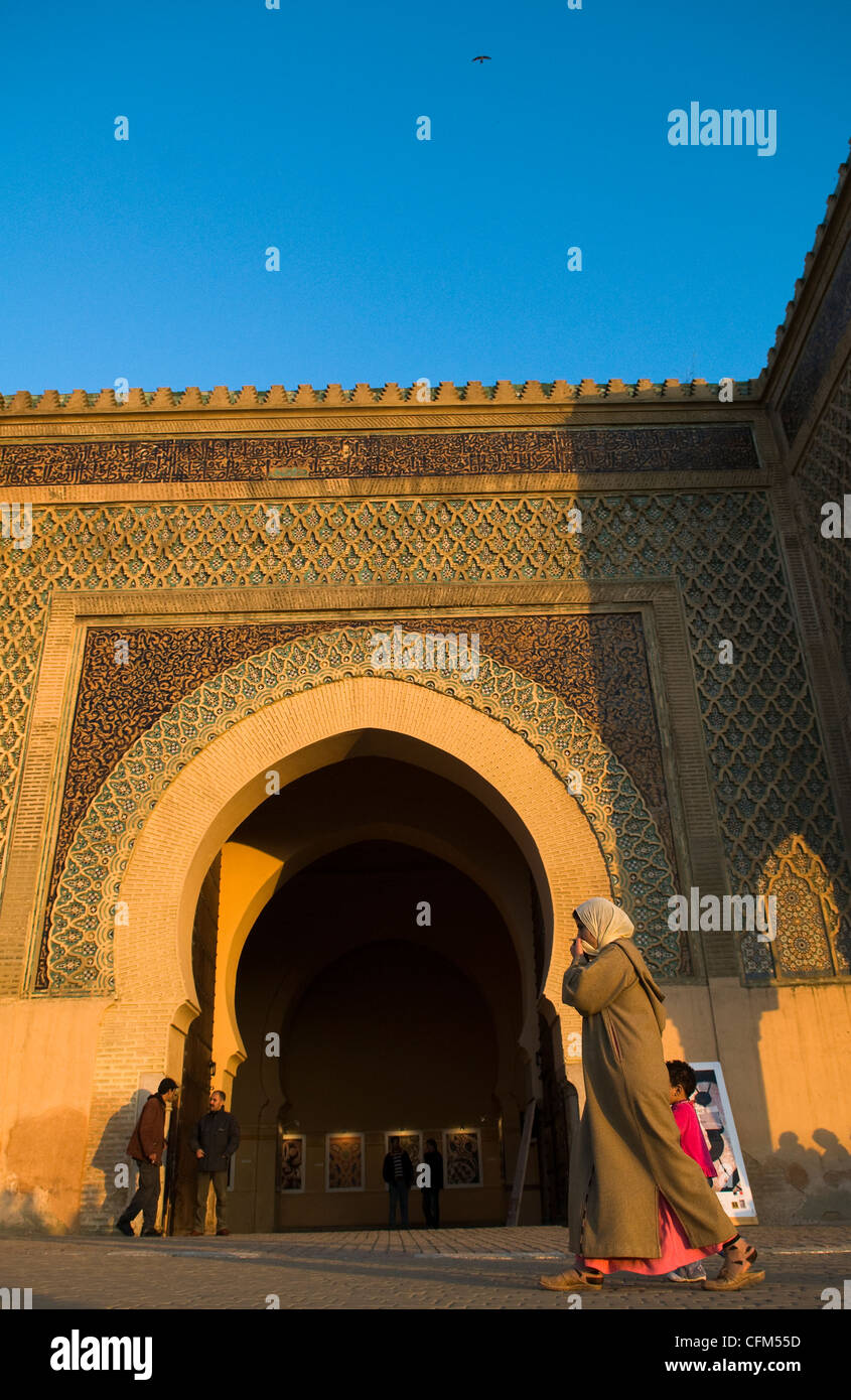A Moroccan woman walking by Bab el-Mansour gate in the old city of Meknes. Stock Photo
