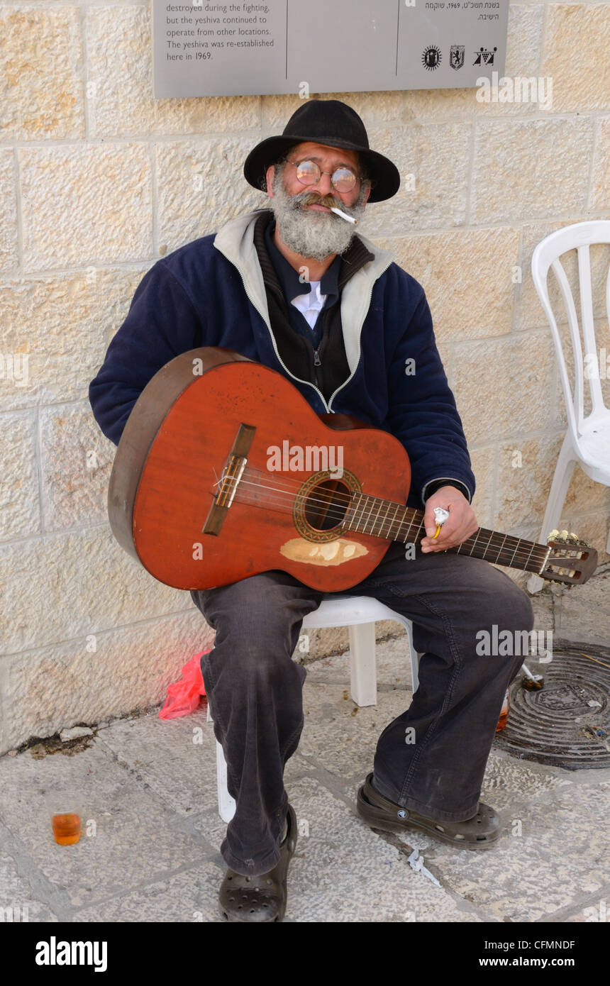Guitarist busking in the Old City of Jerusalem, Israel enjoys a cigarette break. Stock Photo