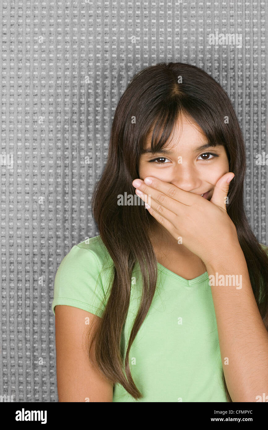 Laughing teenage girl with hands over mouth Stock Photo