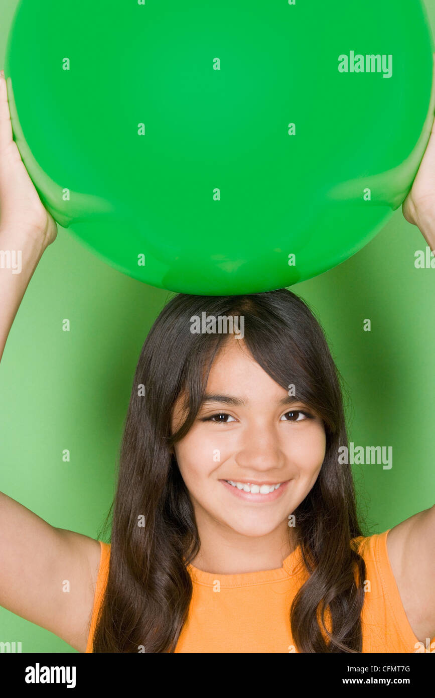 Studio shot portrait of teenage girl holding ball on her head, head and shoulders Stock Photo
