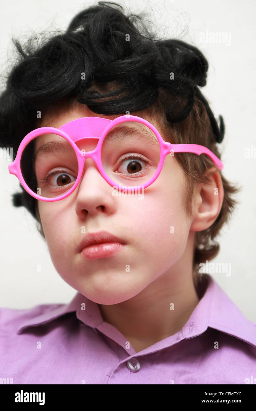 Funny boy plays the fool wearing toy glasses and a doll wig sees