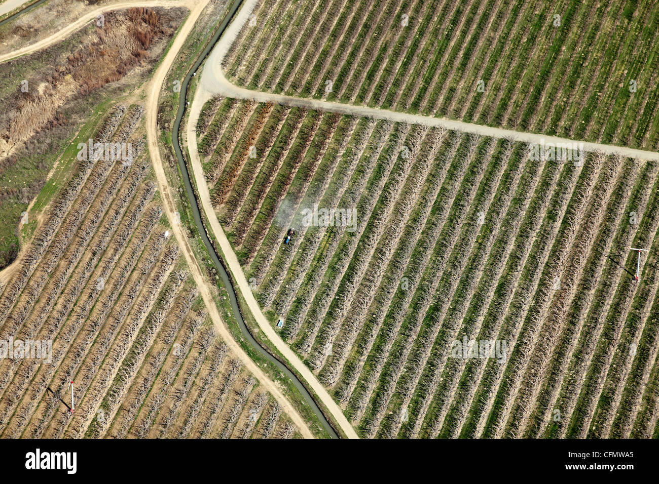 An aerial view of a farmer spraying insecticide on a dormant apple orchard. Stock Photo