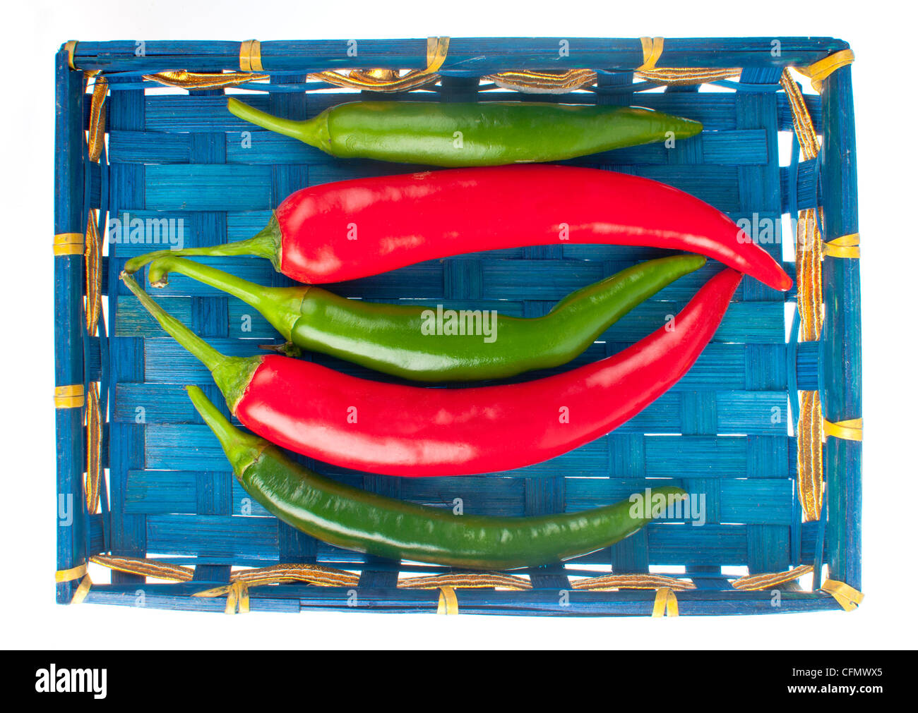 Red and green hot chili peppers in a blue indian basket isolated on ...