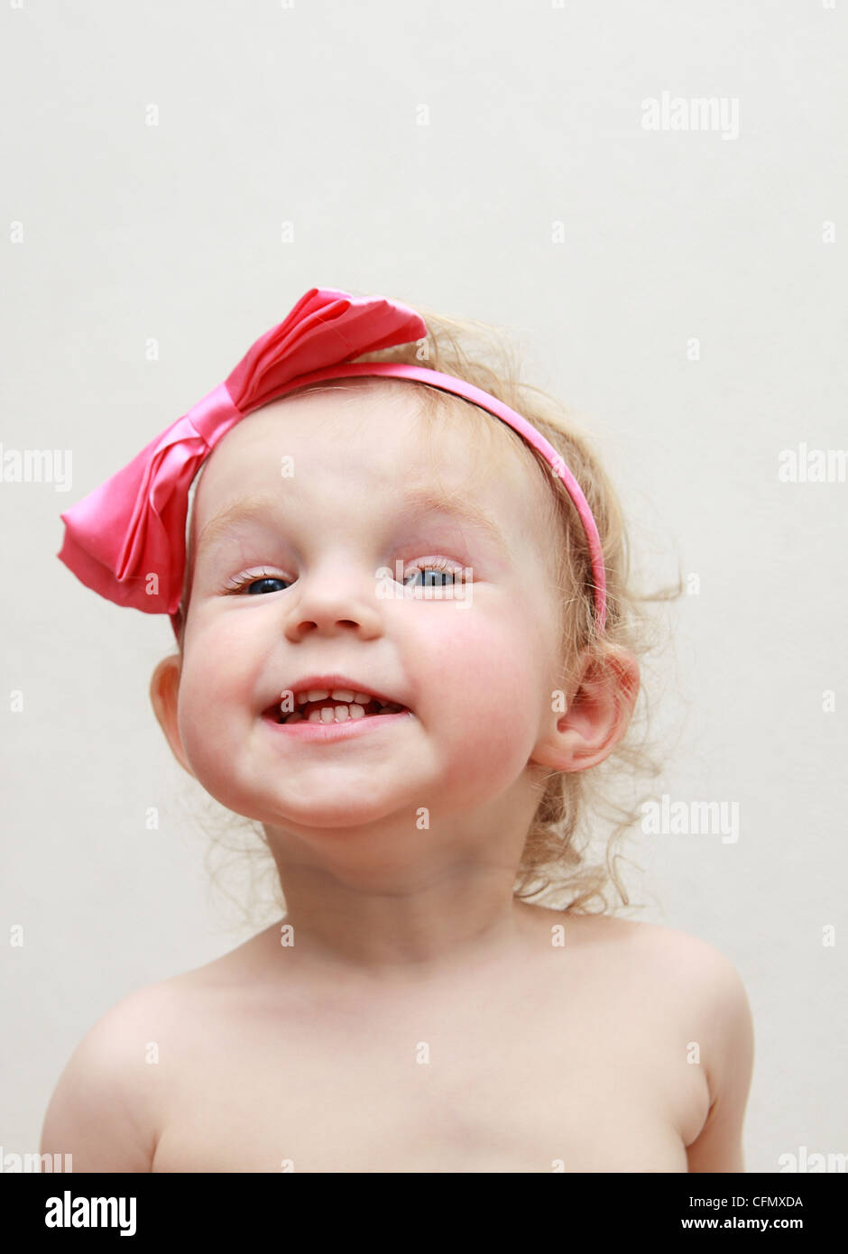 Funny little girl with a pink bow smiles Stock Photo Alamy
