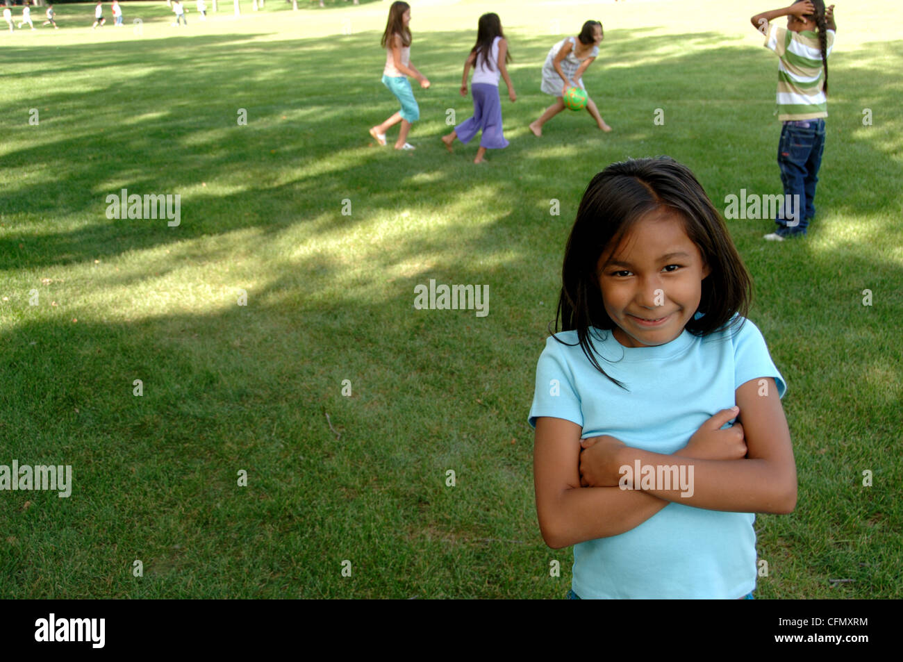 Young Girl in Park, Friends in Background Stock Photo
