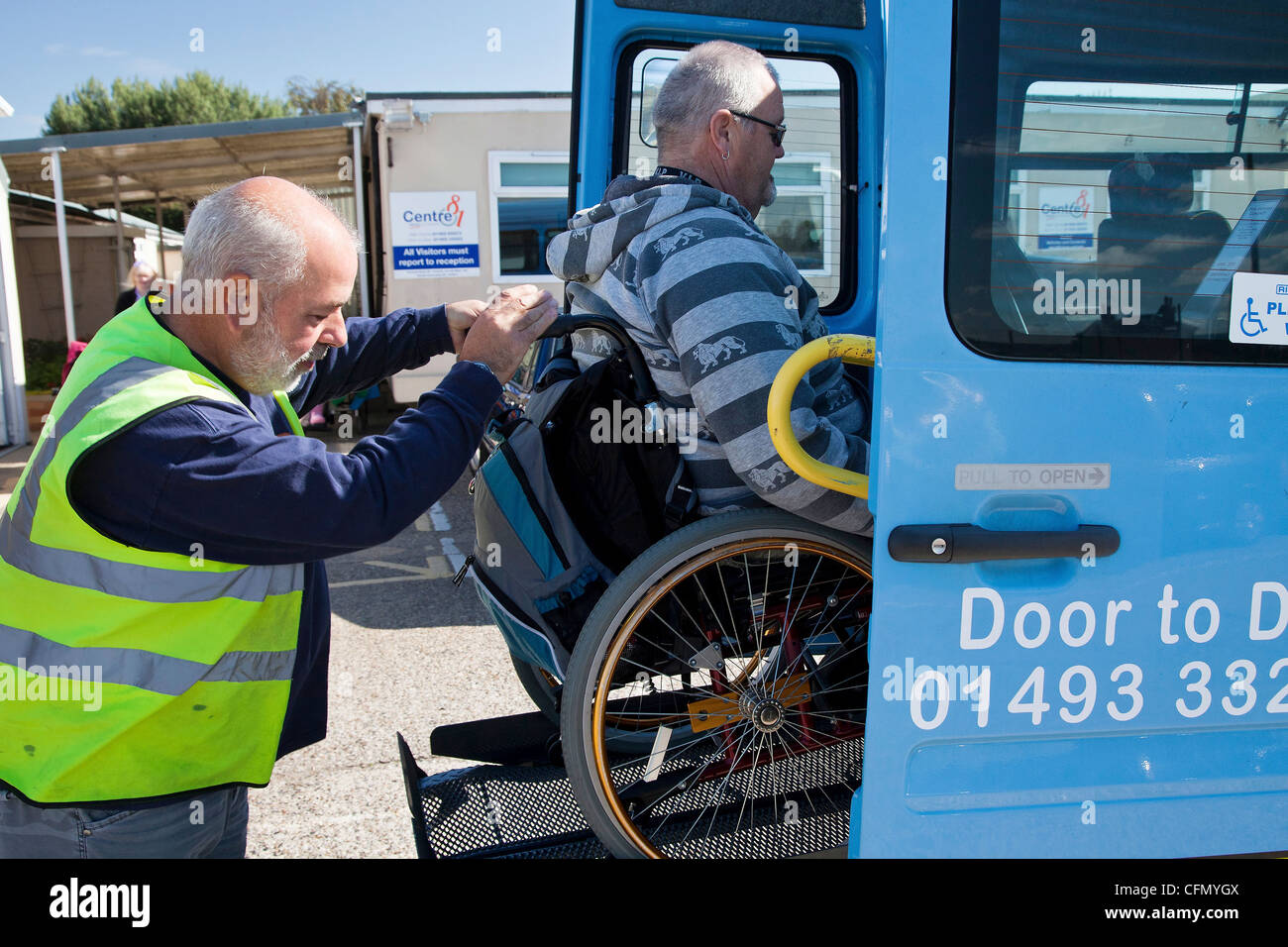 Gentleman in wheelchair being raised up on tail lift of bus Stock Photo