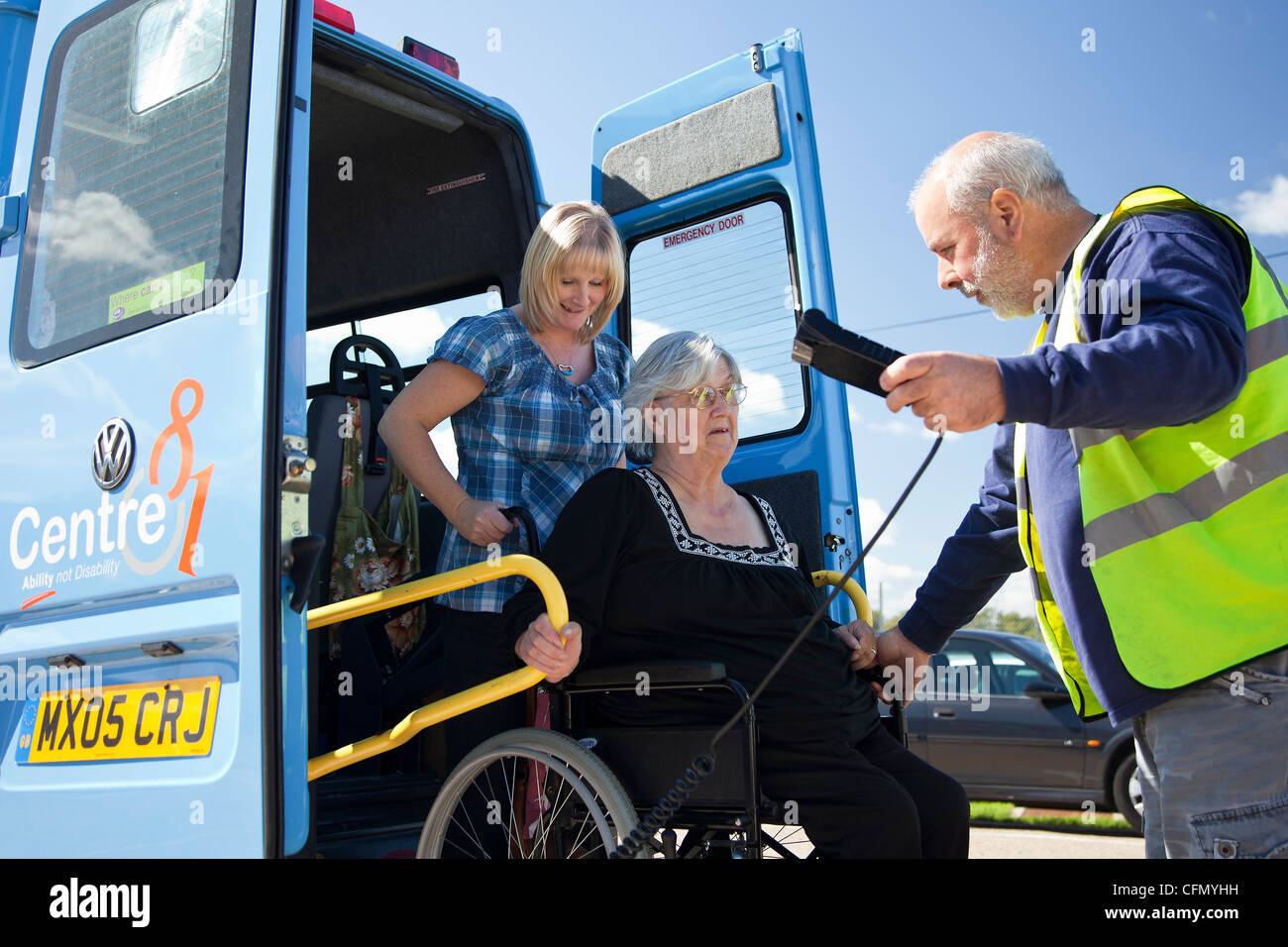 Lady in wheelchair being raised up on tail lift of bus Stock Photo
