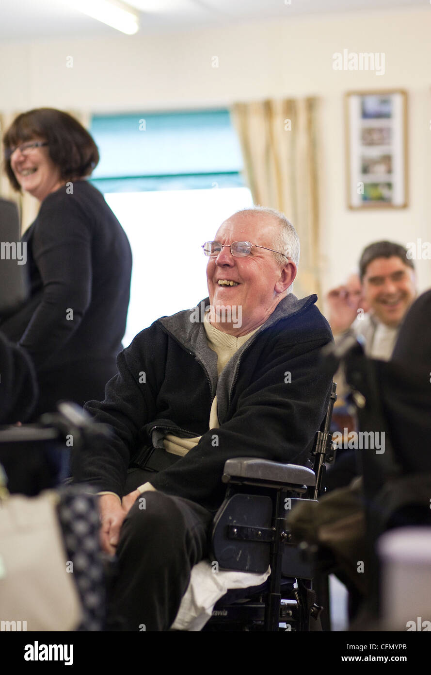 Happy elderly man in wheelchair enjoying activities at disabled support centre. Stock Photo
