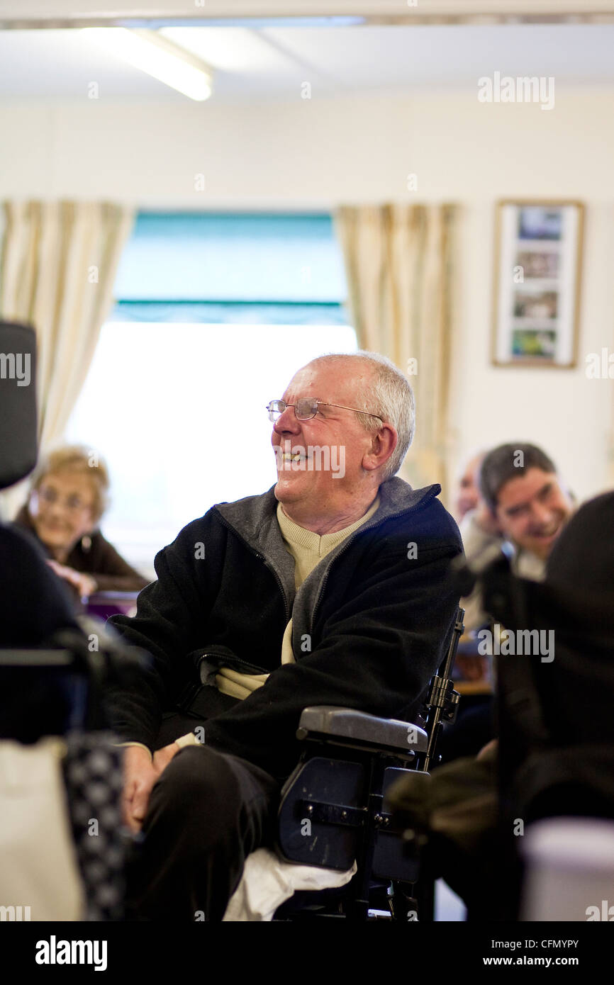 Happy elderly man in wheelchair enjoying activities at disabled support centre. Stock Photo