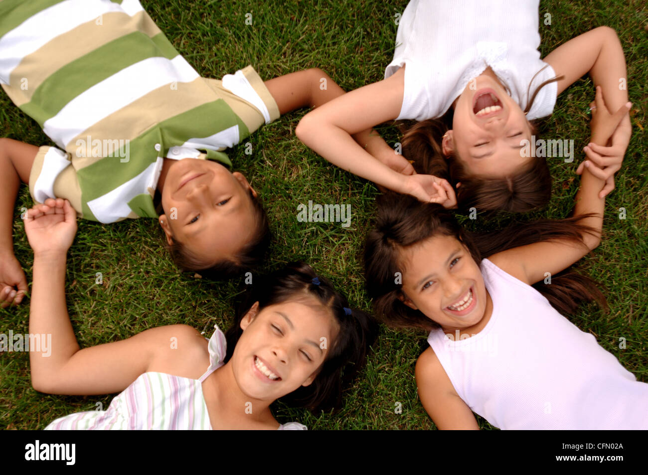 Children Lying in Circle on Grass Stock Photo