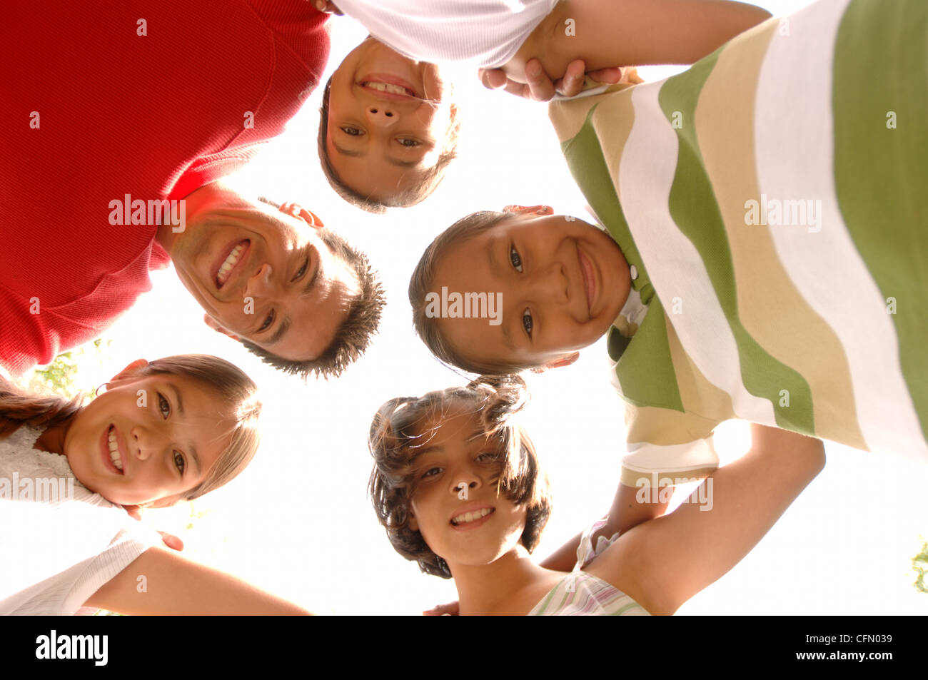 Adult and Children in Circle with Arms Around Each Other Stock Photo