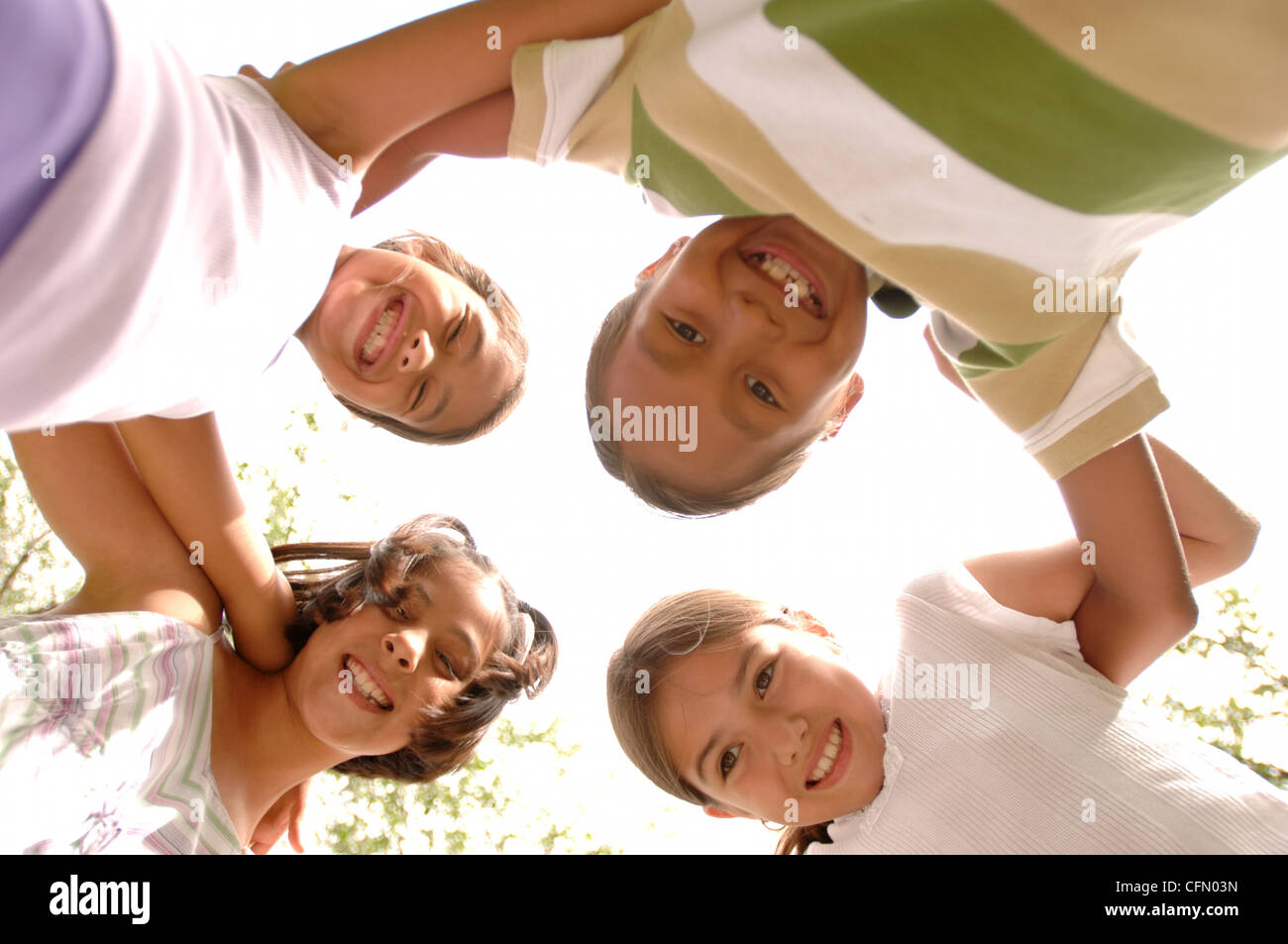 Children Stand in Circle with Arms Around Each Other Stock Photo