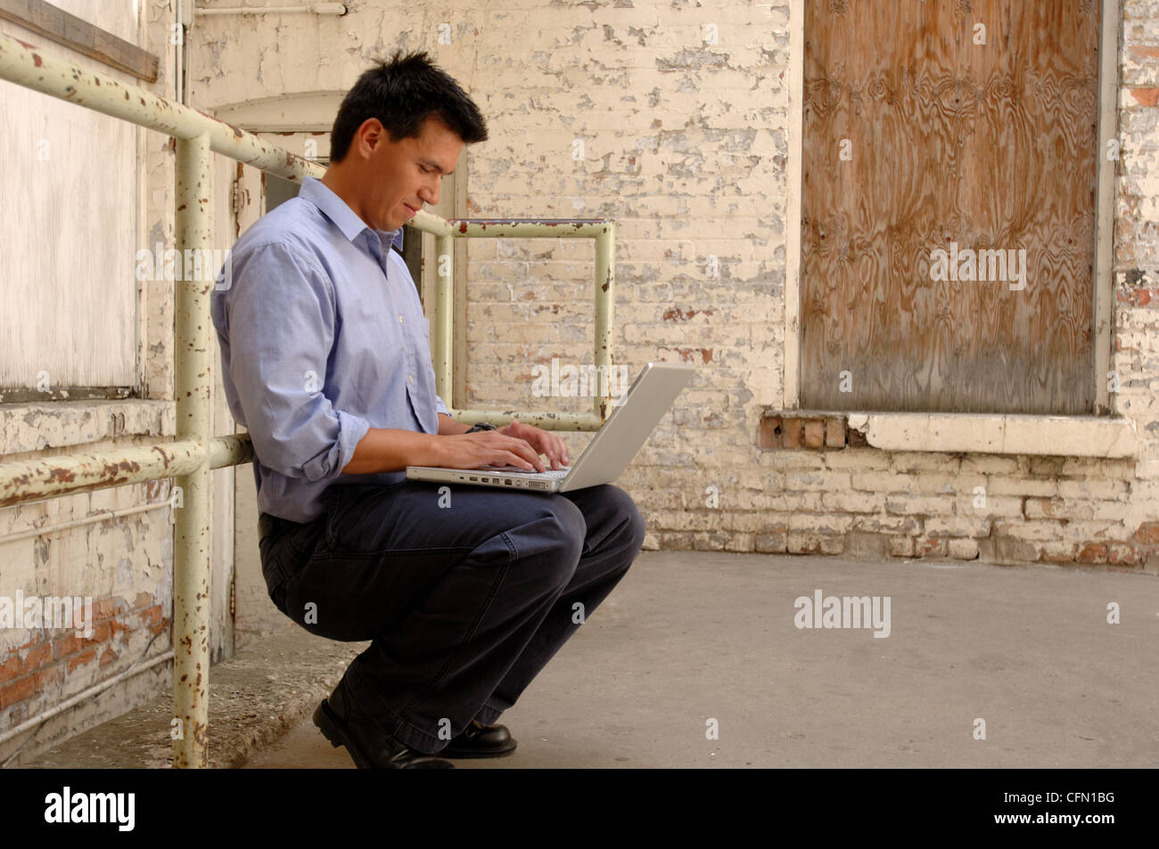 Man Using Laptop in Alley Stock Photo