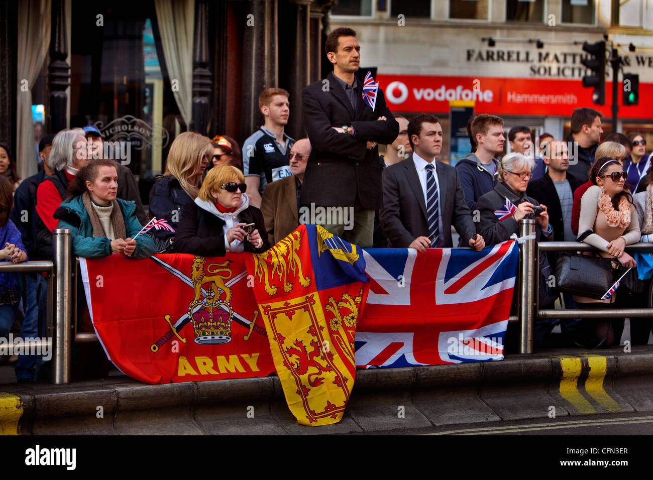 Spectators with patriotic flags watching a parade of the Royal Yeomanry through Hammersmith Stock Photo