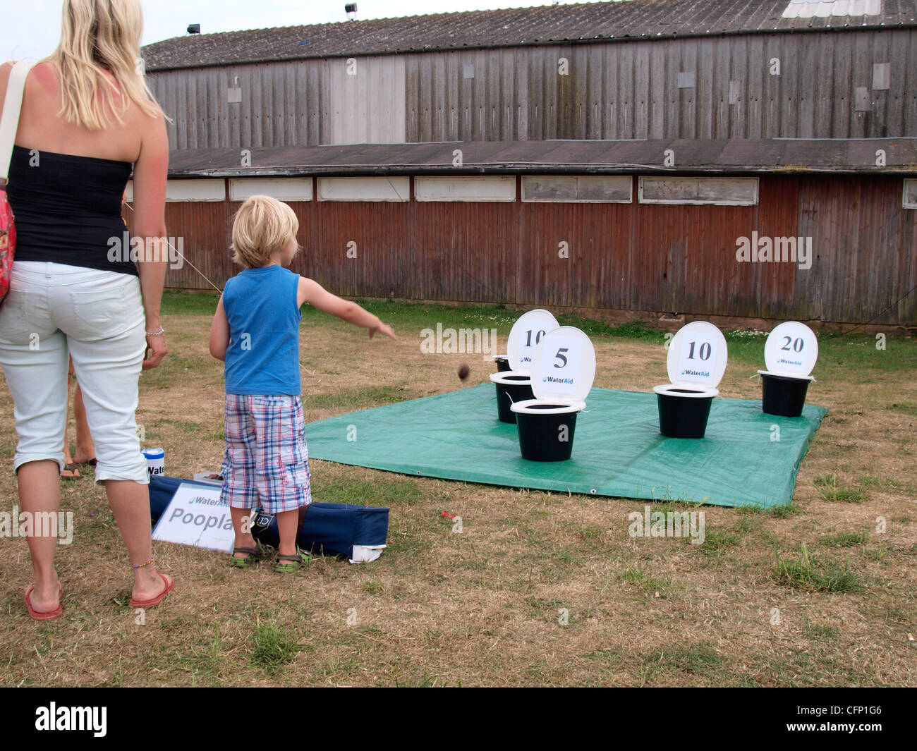Young boy playing Wateraid's game of poopla involving throwing lumps of poo into buckets to raise money, UK Stock Photo