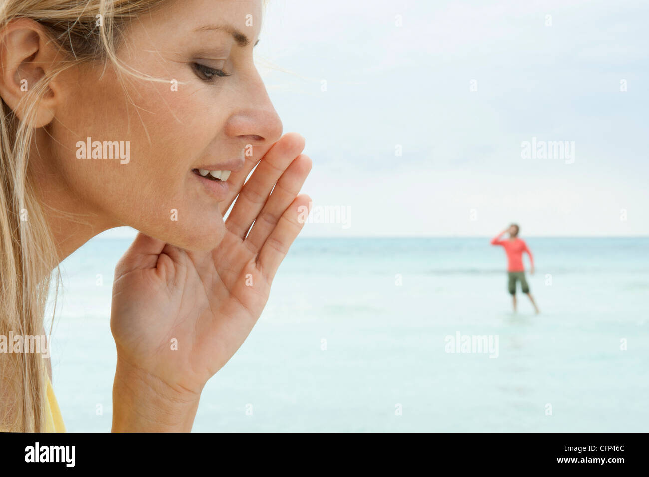 Woman appearing to whisper to tiny man Stock Photo