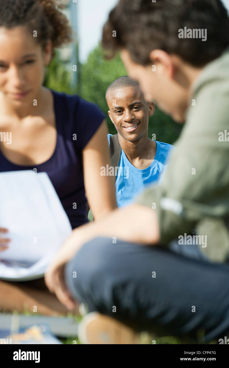 University students studying outdoors, focus on one man in background Stock Photo