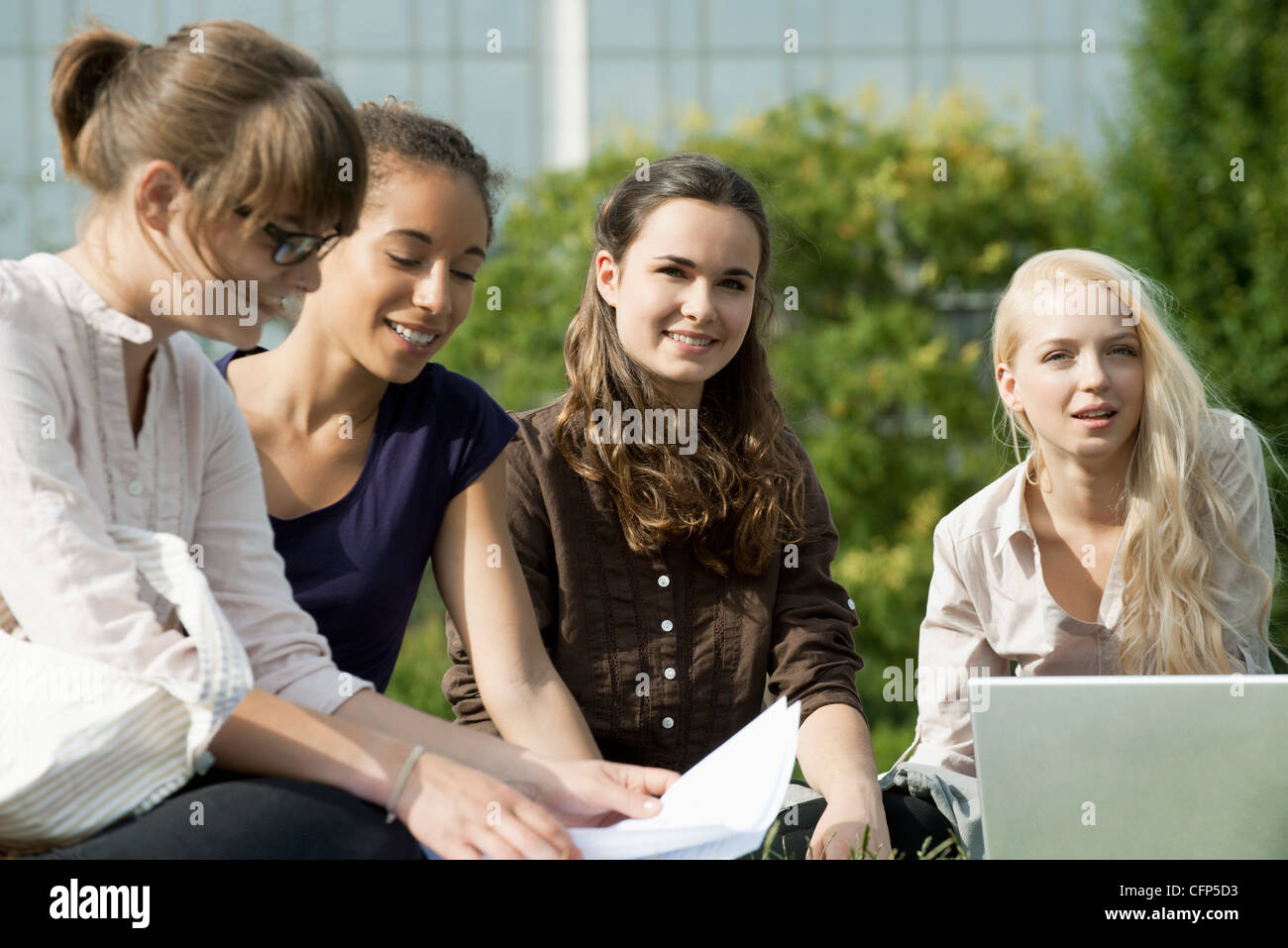 Female university students studying together outdoors, focus on two women Stock Photo