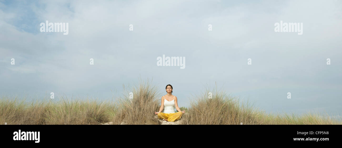 Mature woman meditating on beach Stock Photo