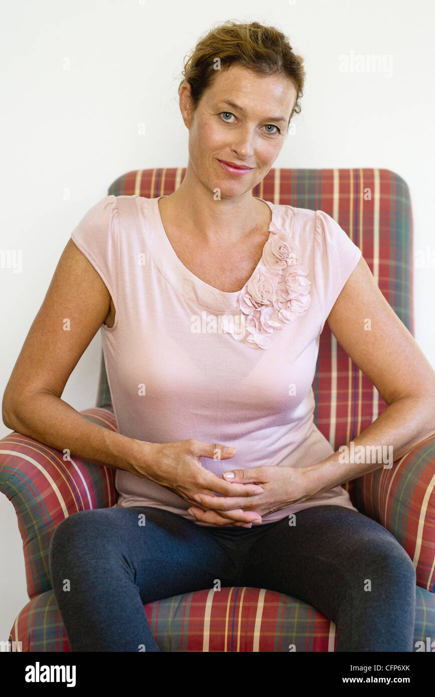 Mature woman sitting in armchair, portrait Stock Photo - Alamy