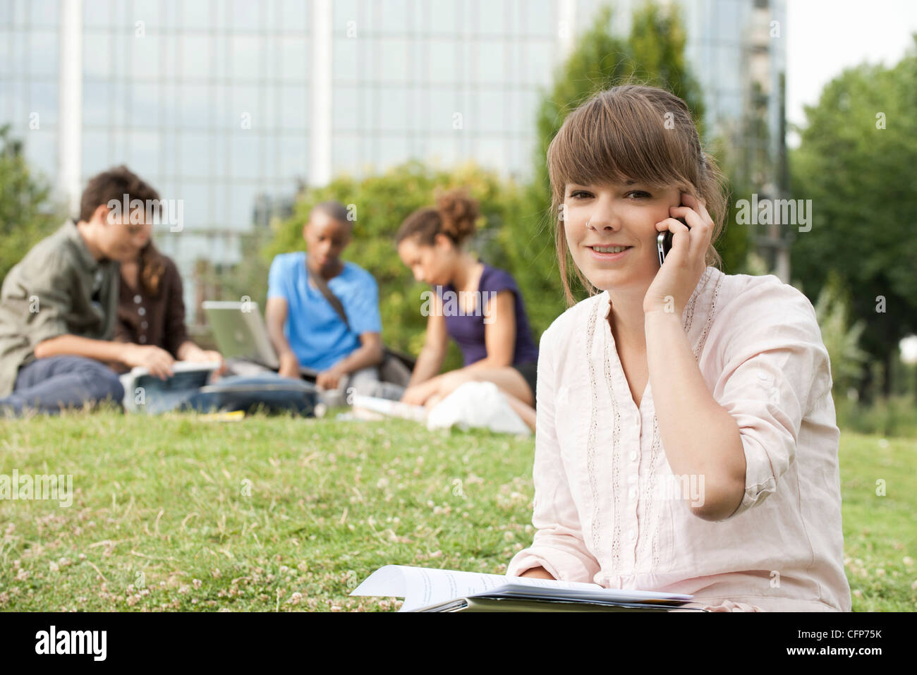 Young woman talking on cell phone, people in background, portrait Stock Photo