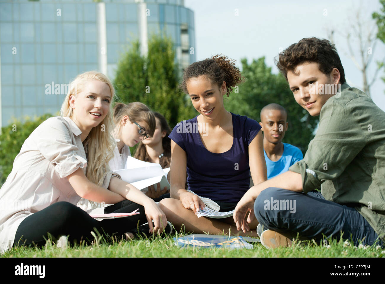 University students studying together outdoors on grass, focus on one woman Stock Photo