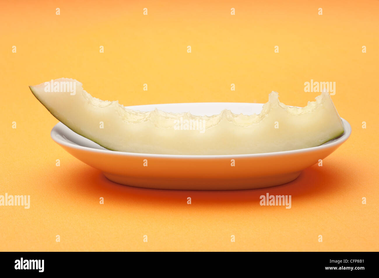 Half eaten slice of melon on a white plate Stock Photo
