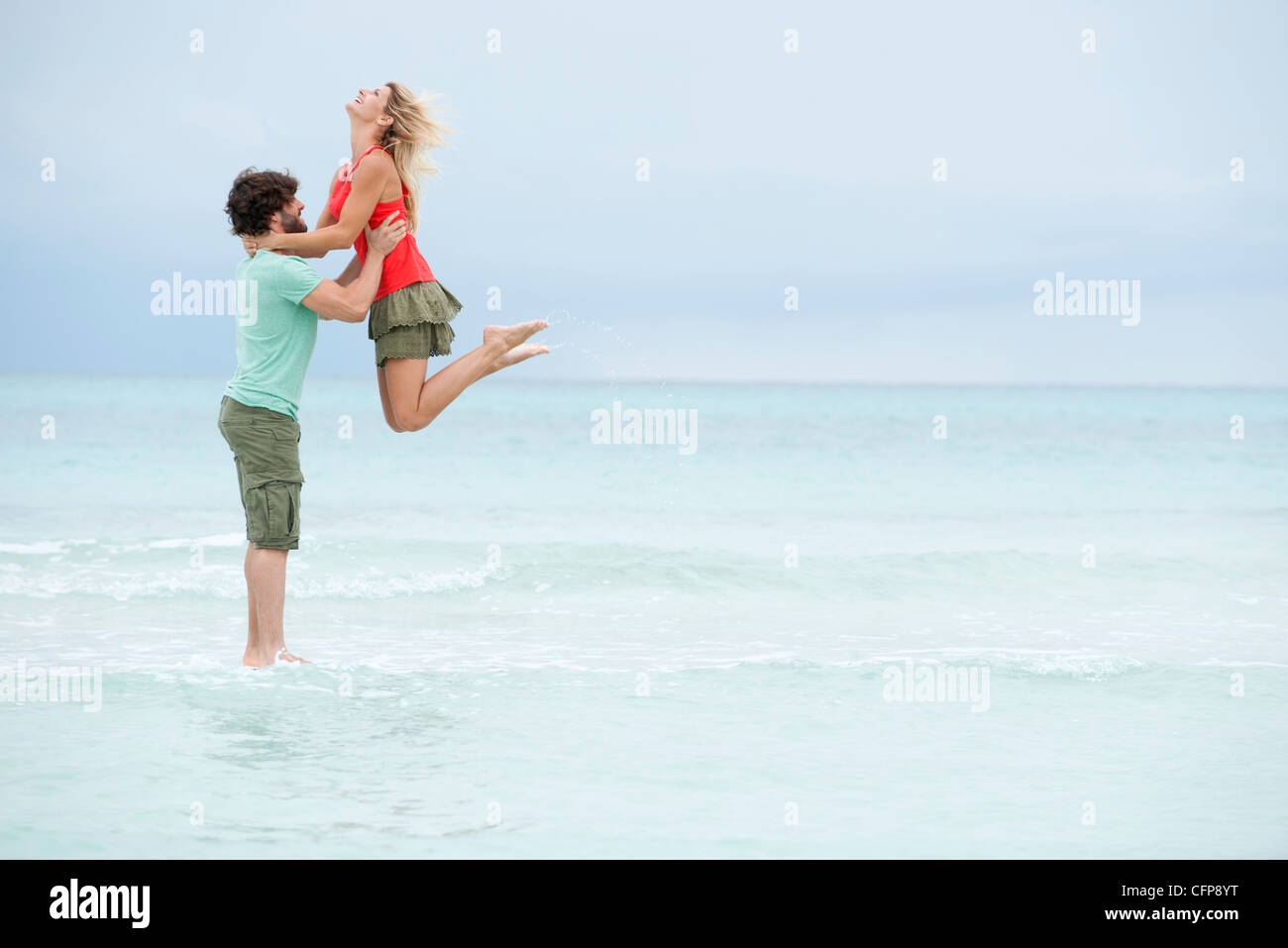 Couple at the beach, man lifting woman in air Stock Photo
