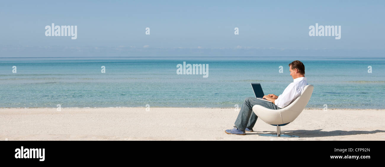 Man using laptop computer at the beach Stock Photo - Alamy