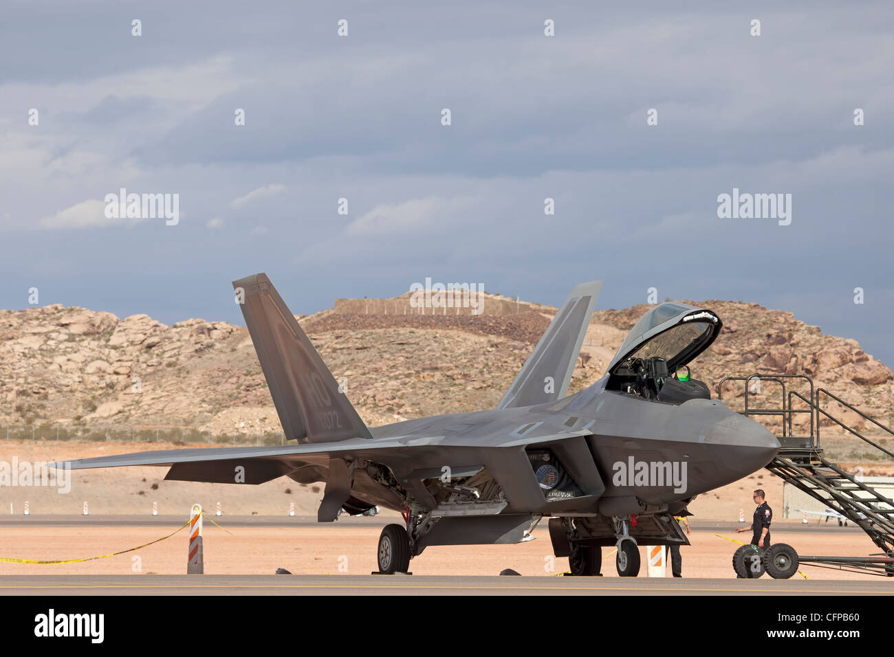 USAF F-22 Raptor air superiority fighter on ground with crew preparing for flight. Runway in desert. Stock Photo