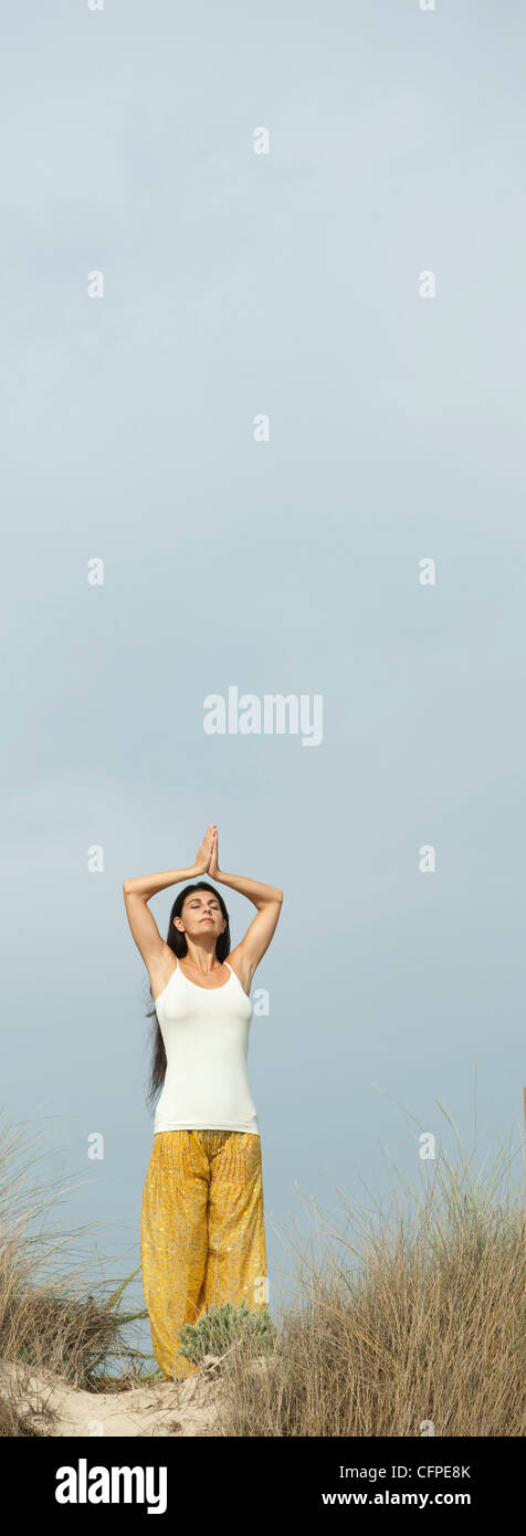 Mature woman doing prayer yoga position on beach Stock Photo