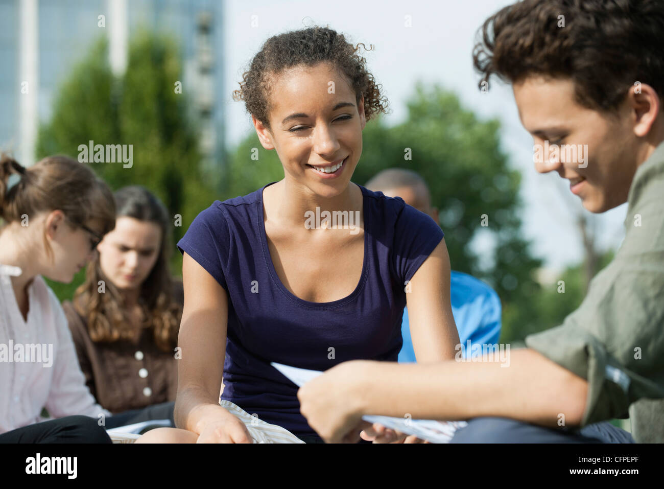 University students studying together outdoors, focus on one woman Stock Photo