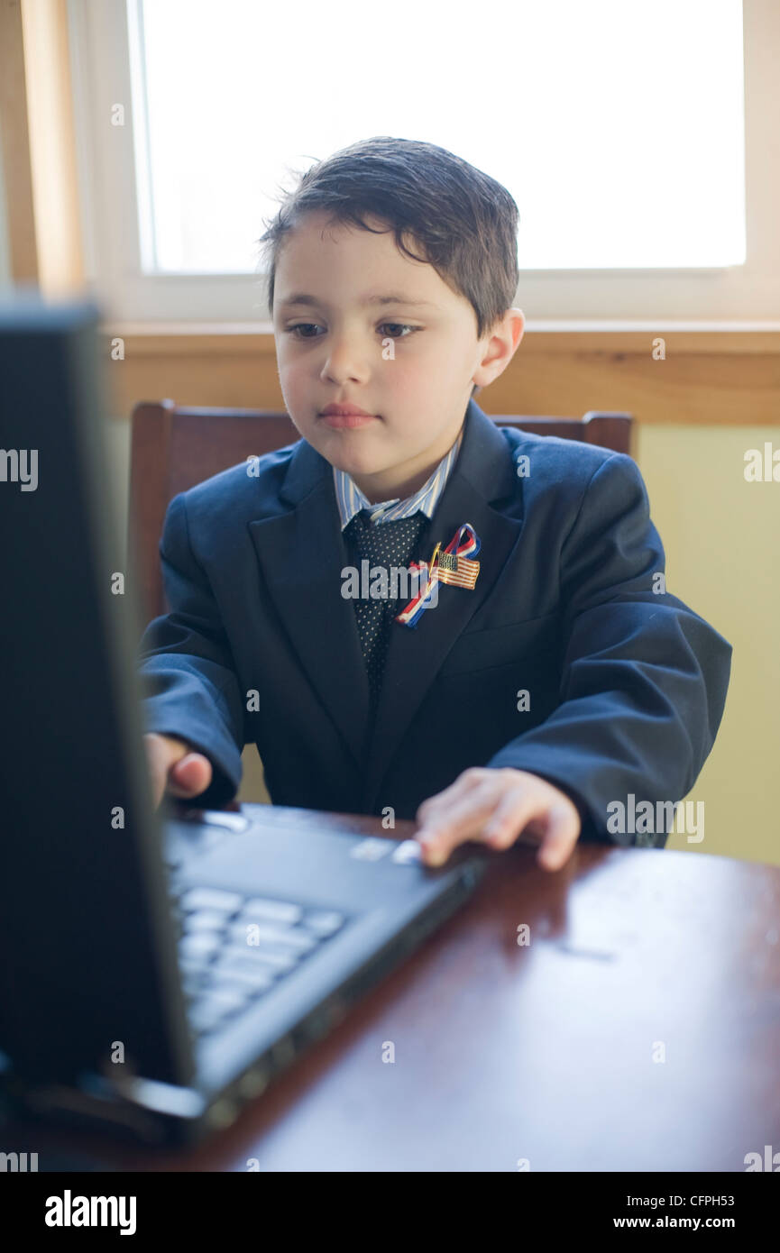 Five year old Hispanic boy formally dressed as a political candidate checks his polling numbers online Stock Photo