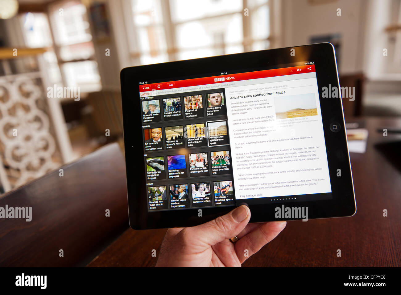 Using Apple's new iPad3 tablet computer to browse the BBC news website, in a cafe bar UK Stock Photo