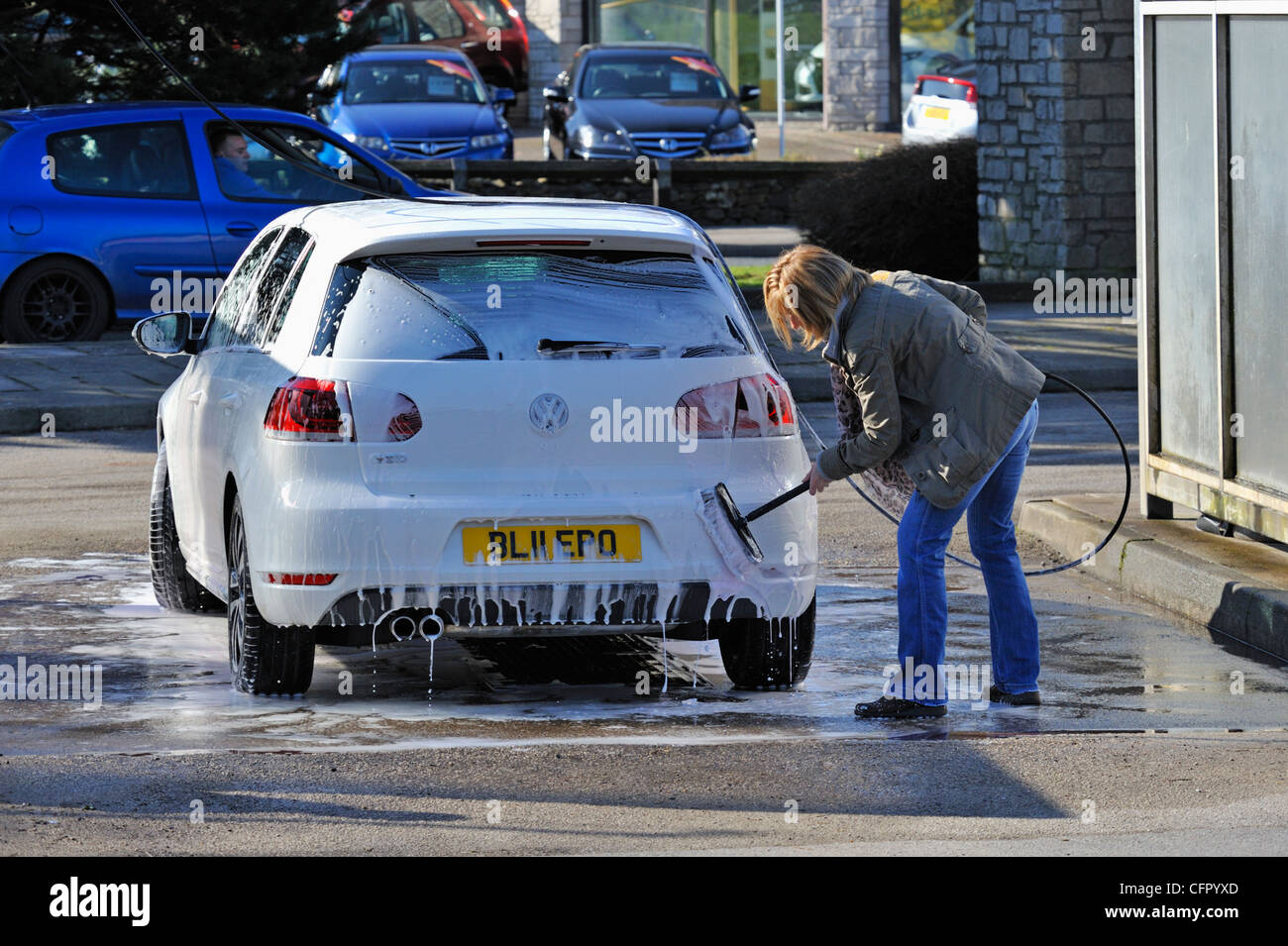 Female motorist using manual car wash. Morrisons Supermarket, Kendal, Cumbria, England, United Kingdom, Europe. Stock Photo