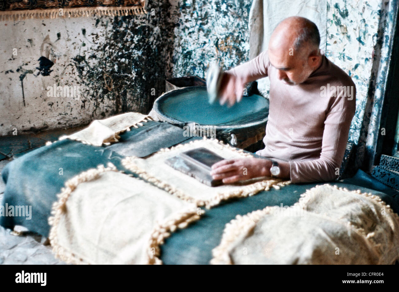 IRAN, ISFAHAN:  Iranian artisan uses a carved wooden block to print a traditional design on placemats in Isfahan Stock Photo