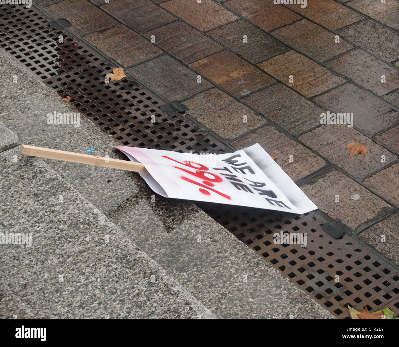 We are the 99% placard discarded on wet steps after a demonstration against government cutbacks. Stock Photo
