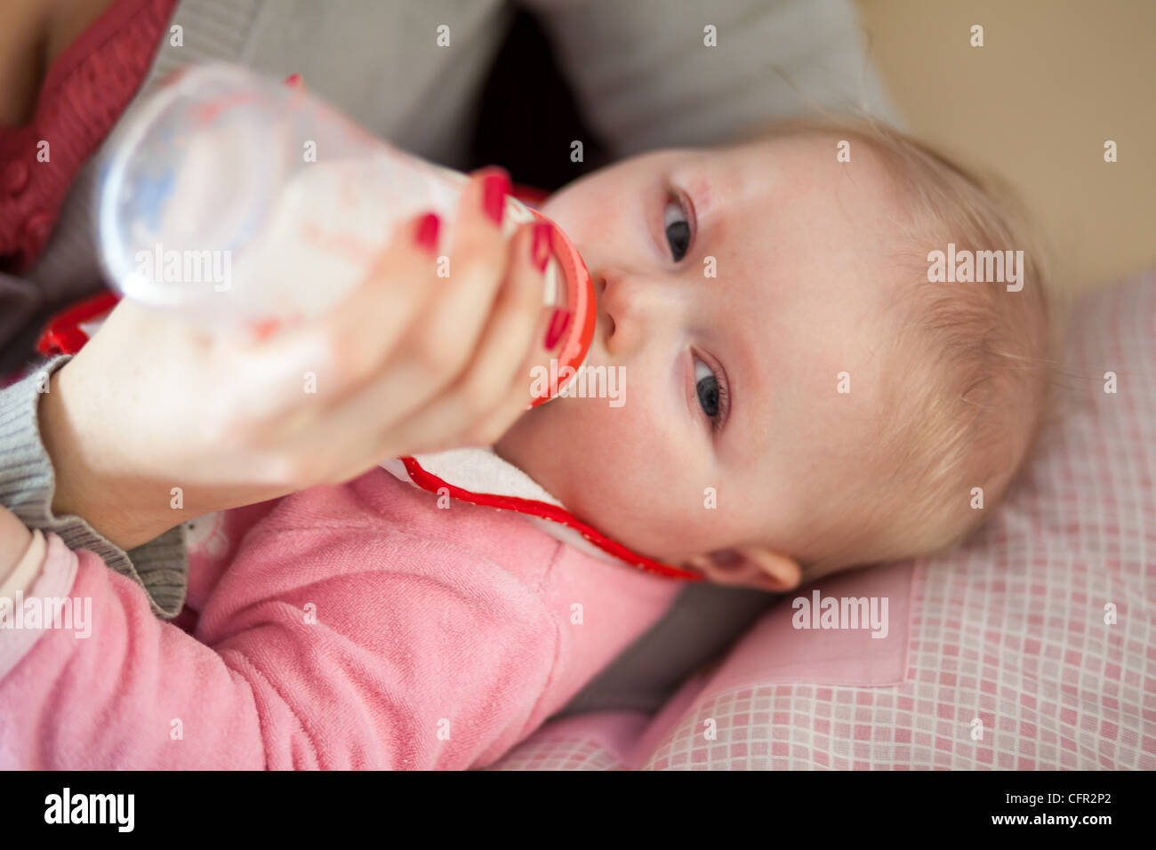 Mother feeding infant girl with baby formula Stock Photo